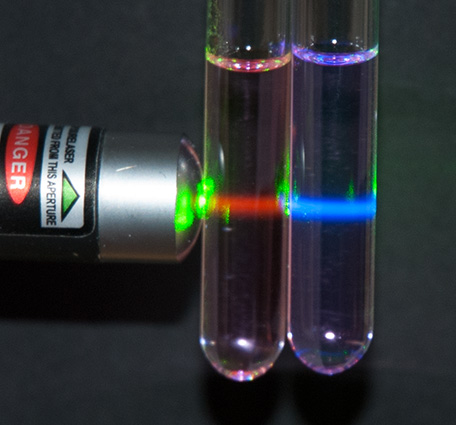 Two vials showing Stokes and anti-Stokes emission under green laser excitation